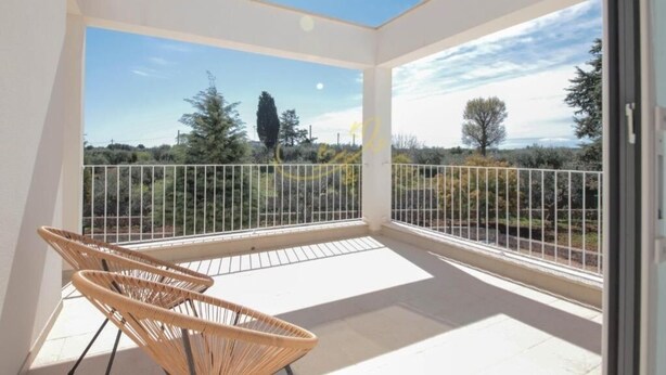A balcony with a view of trees and a clear sky.