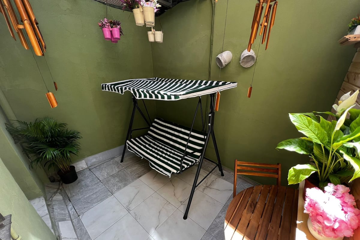 Un petit espace patio avec un ensemble de mobilier d’extérieur à rayures, une table en bois et des plantes en pot.