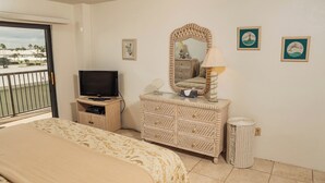A hotel room with a bed, a dresser, a television, and a balcony. - Ocean Delight 2/2 Sandpoint Condo Great OceanViews Pool, Great Rates (Daytona Beach)