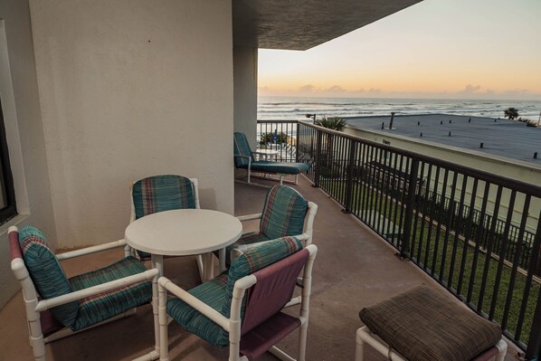 A balcony with two chairs and a table, overlooking the ocean with a view of the beach and distant horizon. - Ocean Delight 2/2 Sandpoint Condo Great OceanViews Pool, Great Rates (Daytona Beach)