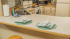 A kitchen with a central island, two wooden stools, a microwave, a coffee maker, and a refrigerator. - Ocean Delight 2/2 Sandpoint Condo Great OceanViews Pool, Great Rates (Daytona Beach)