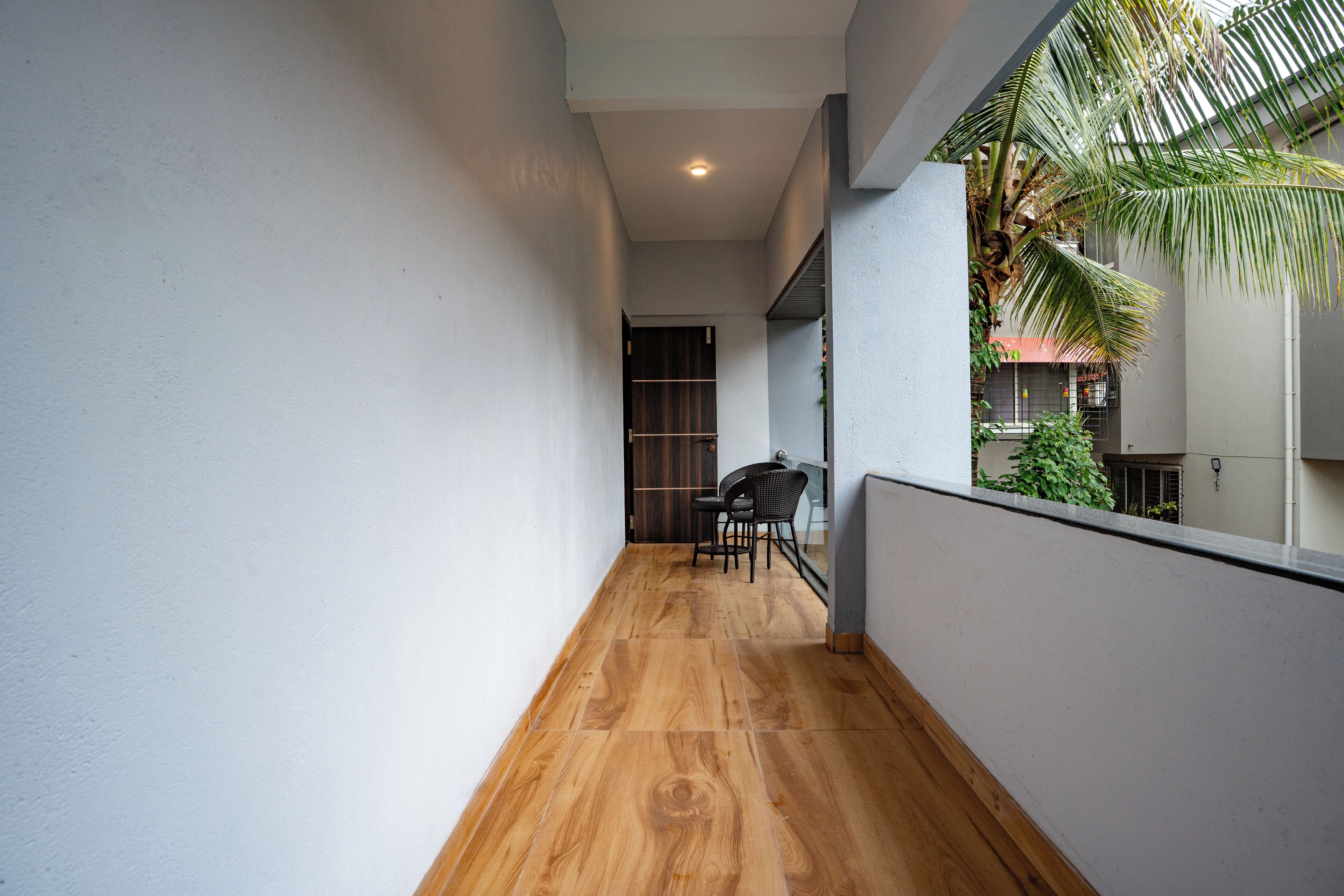 A narrow corridor with wooden flooring, a chair, and a table.
