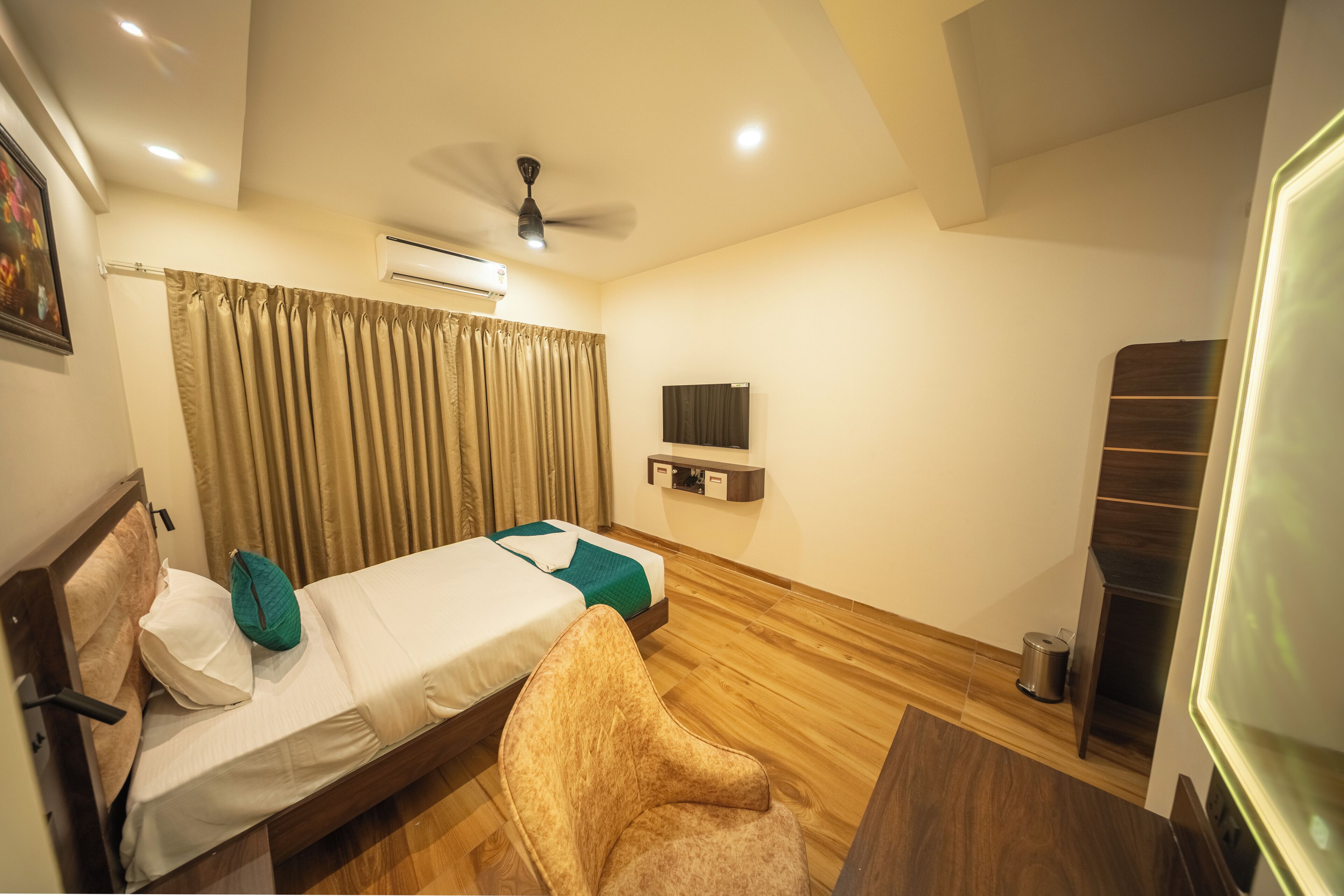 Habitación de hotel con dos camas, ventilador de techo, aire acondicionado, televisor y piso de madera.