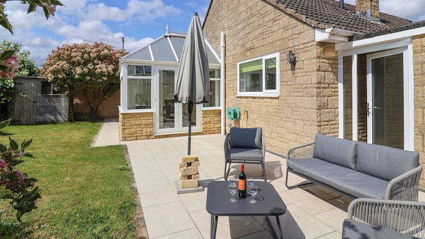 A patio with a table, chairs, and a glass-enclosed room.