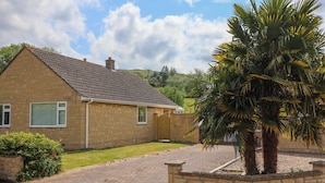 A two-story house with a tiled roof, a front garden, and a palm tree.