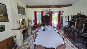 Comedor con una mesa grande, sillas, chimenea y una araña.