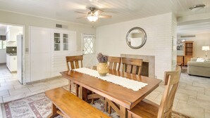 Uma área de refeições com mesa e cadeiras de madeira, ventilador de teto e lareira.