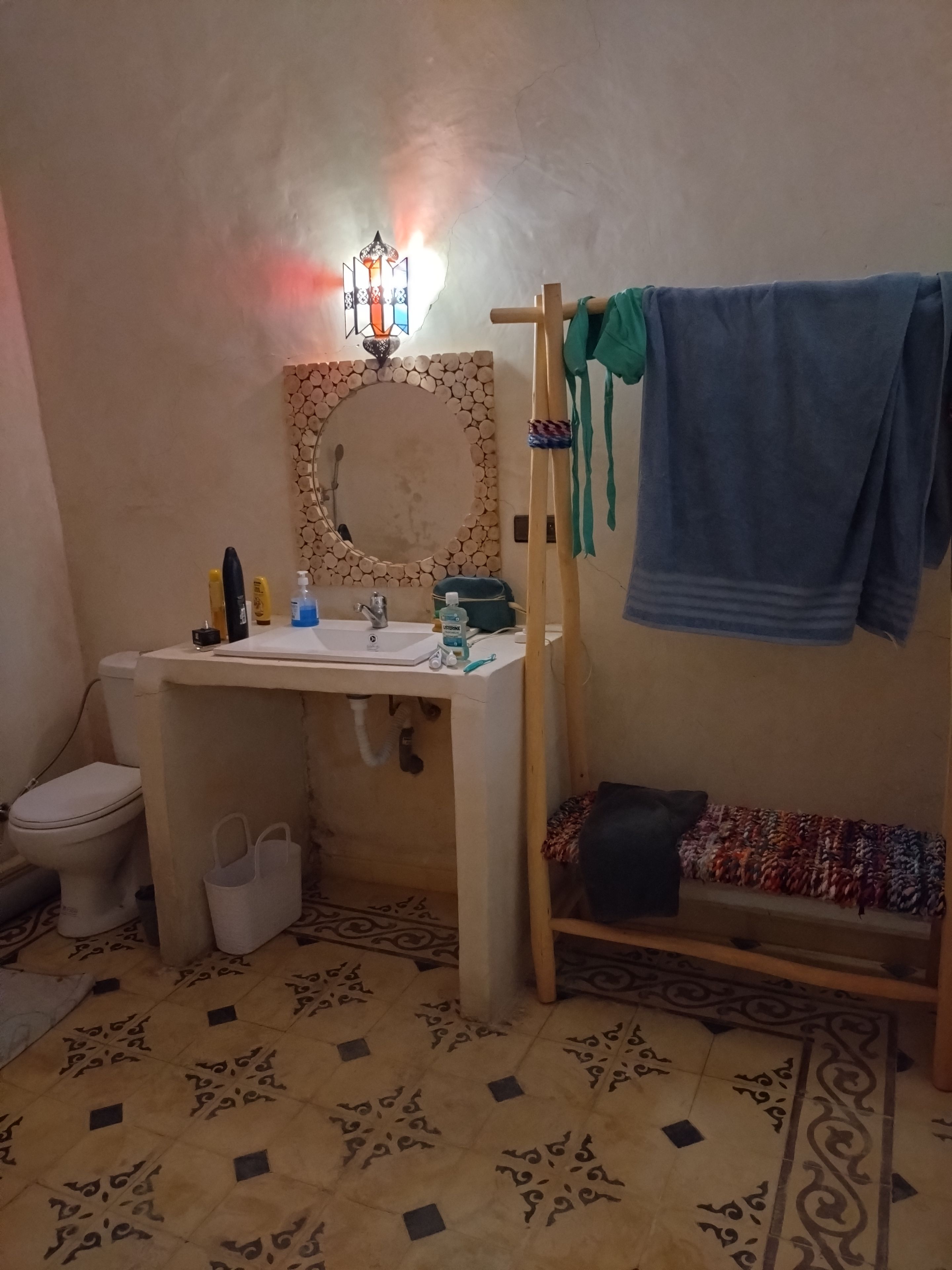Une salle de bain avec un lavabo, des toilettes et une étagère en bois sur laquelle est posée une serviette.