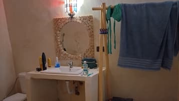Une salle de bain avec un lavabo, des toilettes et une étagère en bois sur laquelle est posée une serviette.
