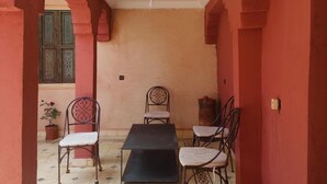 A corridor with a tiled floor, a table, and two chairs. - RIAD Beautiful Places  (Tahannaout)