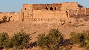 A historical building with arched windows and a flat roof, surrounded by sparse vegetation. - RIAD Beautiful Places  (Tahannaout)