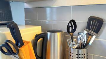 A kitchen counter with a kettle, a knife block, and a utensil holder.