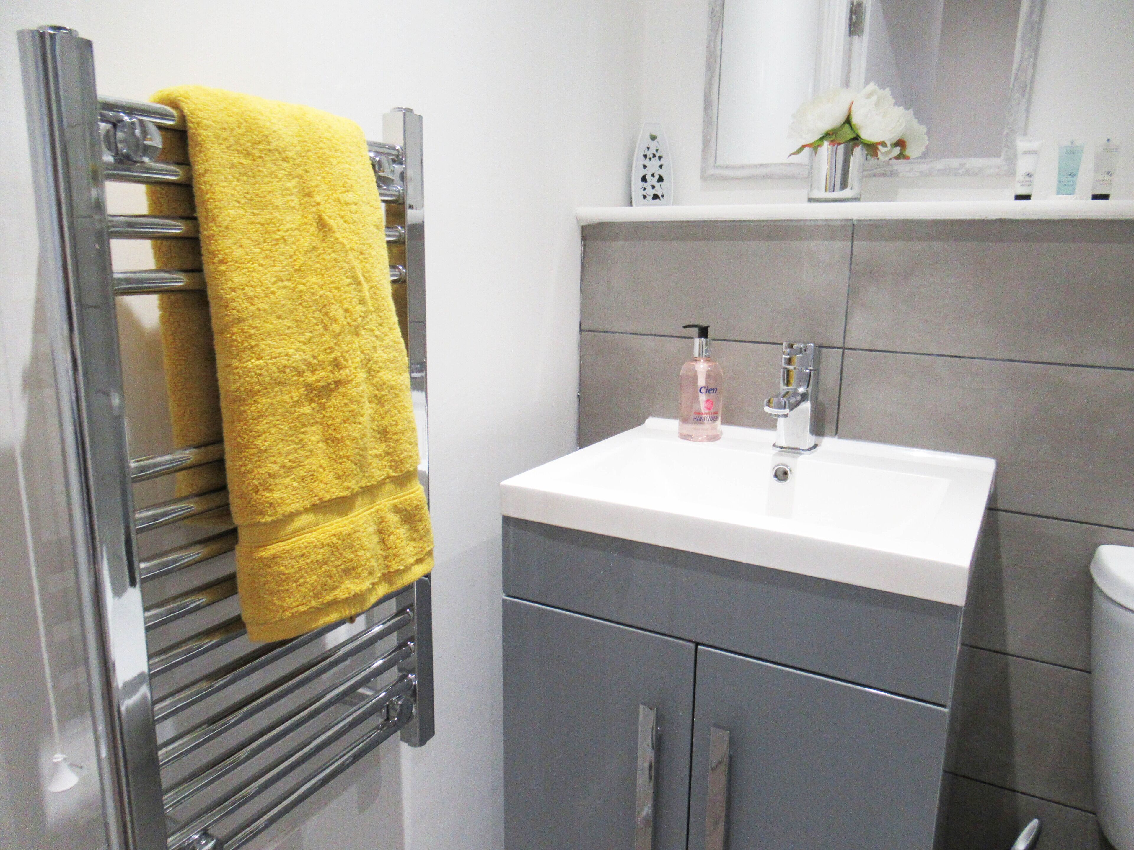 Un baño con toallero, lavabo y artículos de aseo.