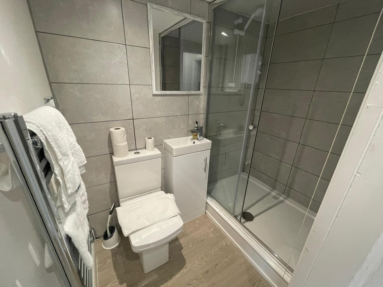 Une salle de bain moderne équipée de toilettes, d’un lavabo et d’une douche à parois en verre.