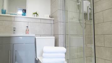 Une salle de bain moderne avec une douche à parois de verre, des toilettes et un lavabo surmonté d’un miroir.