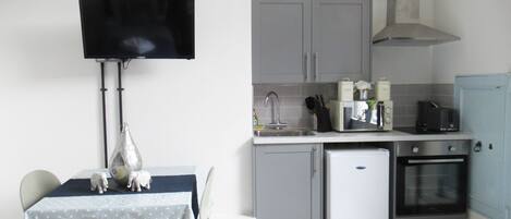 A compact kitchen with a dining area, a small refrigerator, a microwave, and a sink.