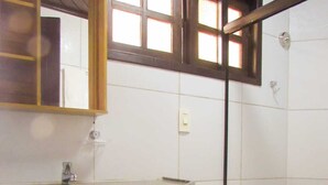 A bathroom with a granite countertop sink, a mirror, and a shower area with tiled walls. - Suites Pontal dos Golfinhos (Ipojuca)
