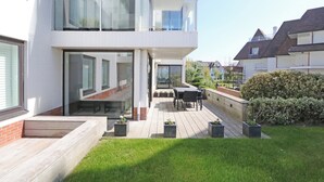 Ein modernes, zweistöckiges Haus mit Balkon, Außenbereich und gepflegtem Garten.