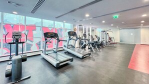 A gym with treadmills, a stationary bike, and a rowing machine. - Chic Marina Arcade Apartment Minutes to Beach (Dubai)
