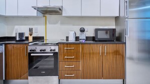A kitchen with a Bosch oven, wooden cabinets, a microwave, and a stainless steel refrigerator. - Chic Marina Arcade Apartment Minutes to Beach (Dubai)