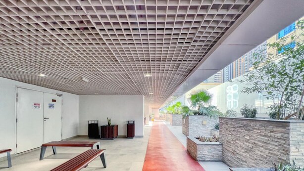 A corridor with benches, a red pathway, and planters with greenery. - Chic Marina Arcade Apartment Minutes to Beach (Dubai)