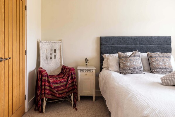 A bedroom with a bed, a nightstand, a chair, and a wooden door.