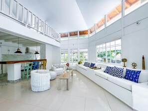 Un intérieur spacieux et bien éclairé, avec un plafond haut, des murs blancs et de grandes fenêtres.