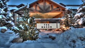 A hotel named "The Mason" with a prominent entrance, surrounded by snow-covered trees and a snowy landscape. - Moose Mgmt-The Mason 3053 (Park City)
