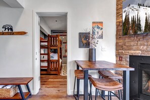 Ein gemütlicher Raum mit Holztisch, Bänken, Kamin und Bücherregal.