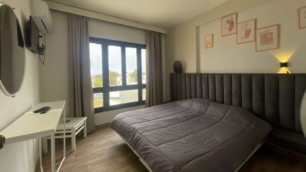Une chambre d’hôtel moderne avec un grand lit, un bureau et une fenêtre avec des rideaux.