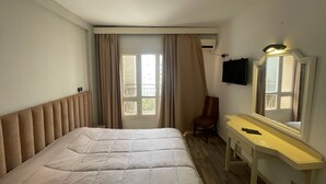 Une chambre d’hôtel équipée d’un lit, d’un bureau, d’une chaise, d’une télévision et d ’une fenêtre avec des rideaux.