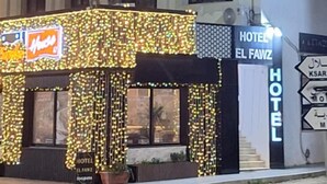 Un immeuble abritant un hôtel à plusieurs étages, doté d’une enseigne lumineuse et d’un panneau indiquant l’emplacement d’un restaurant situé à proximité.