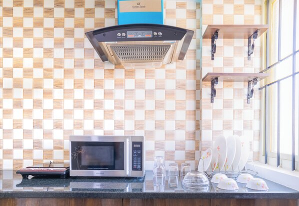 A kitchen with a microwave, a coffee maker, and a window with a view of the outside.