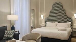 Une chambre d’hôtel avec un grand lit, un bureau avec une chaise, une lampe et un miroir.