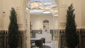 Une entrée agrémentée de ferronnerie ouvragée, un coin repas avec une table ronde et des chaises, et des plantes en pot.