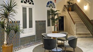 Un hall d’entrée avec une table ronde et des chaises, un escalier et des murs décorés de motifs.