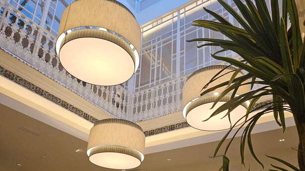 Un vaste atrium doté d’un haut plafond, de balustrades décoratives et de nombreuses lampes suspendues.