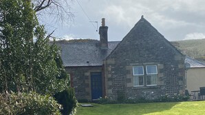 A stone house with a well-maintained lawn and a garden with various plants.