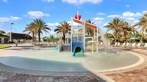 A water play area with a slide and splash zone, surrounded by palm trees and lounge chairs. - Spacious Villa w/ Pool, Theater & Game Room (Davenport)