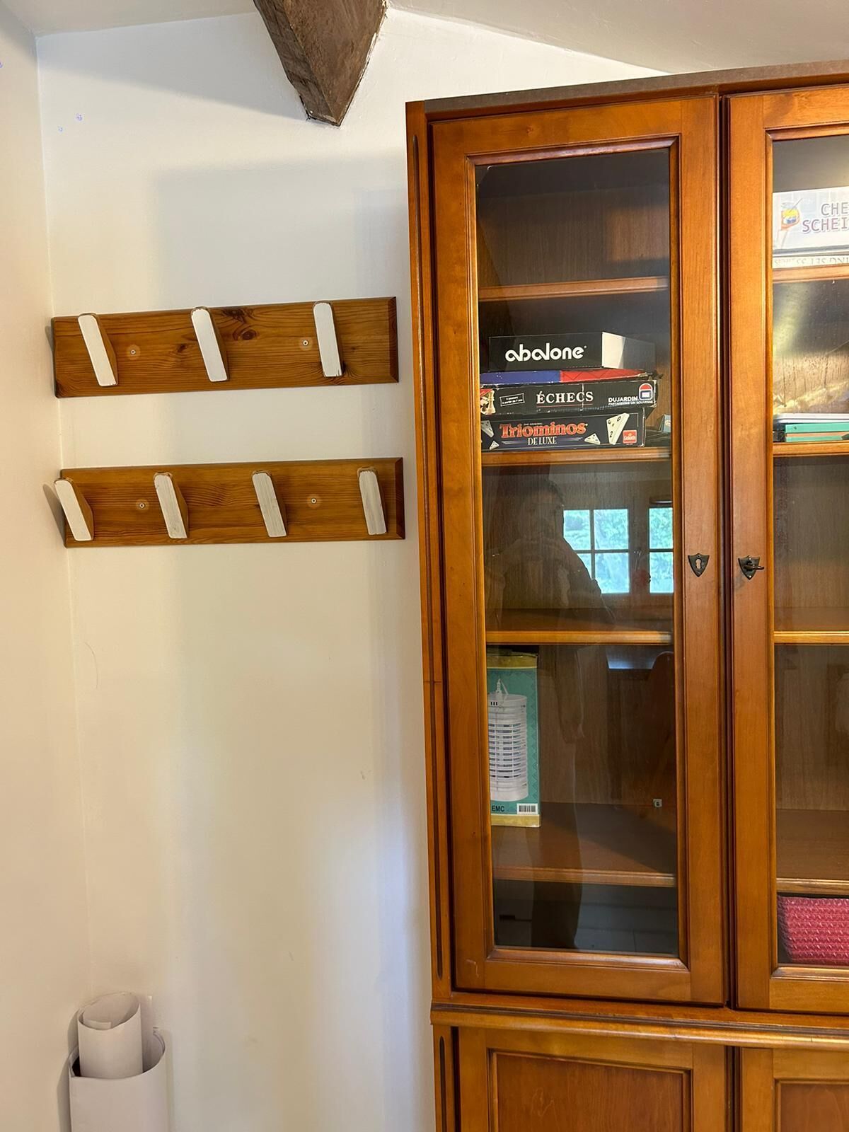 A wooden cabinet with glass doors containing books and a small sign.