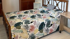 A bedroom with a bed, wooden headboard, a nightstand, a wardrobe, and a wall-mounted lamp. - Villa F3 entre mer et Montpellier (Lattes)