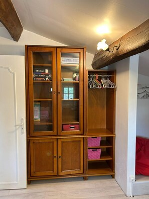 Guarda-roupa de madeira com várias prateleiras, gavetas e um cabideiro, além de uma pequena janela.