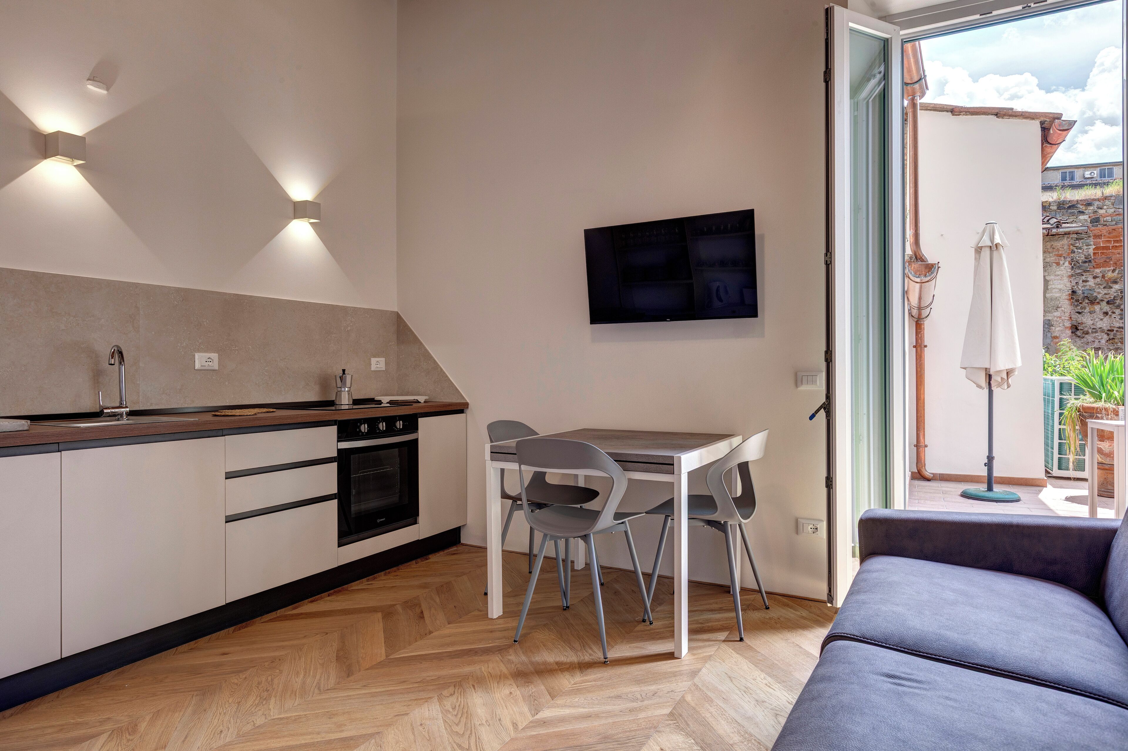A modern kitchen with a dining area, a flat-screen TV, and a view of the outside.