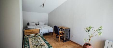 A bedroom with a bed, a desk, a chair, and a potted plant.