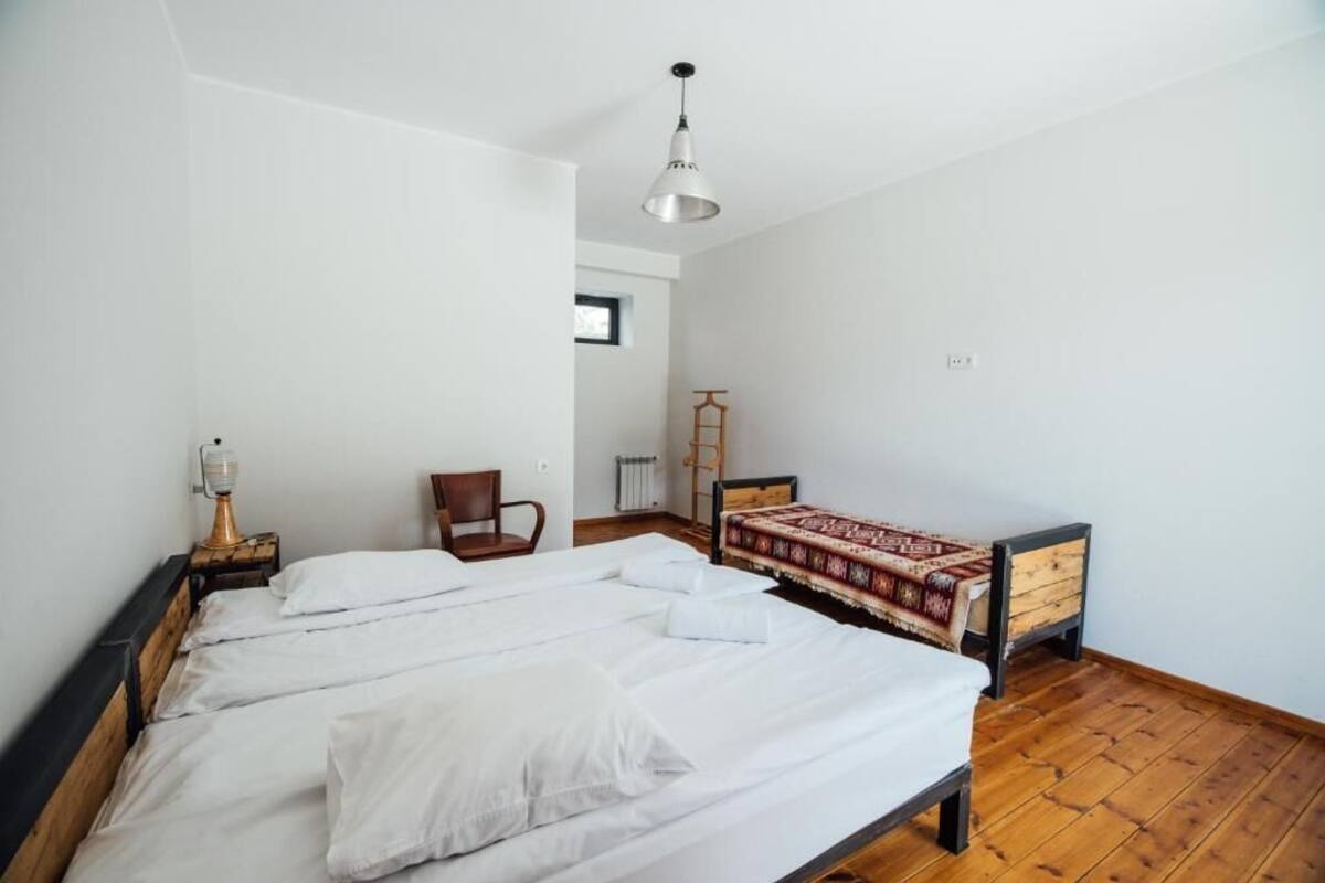 Ein Zimmer mit einem großen Bett, einem Sessel, einer Lampe und einem Heizkörper.