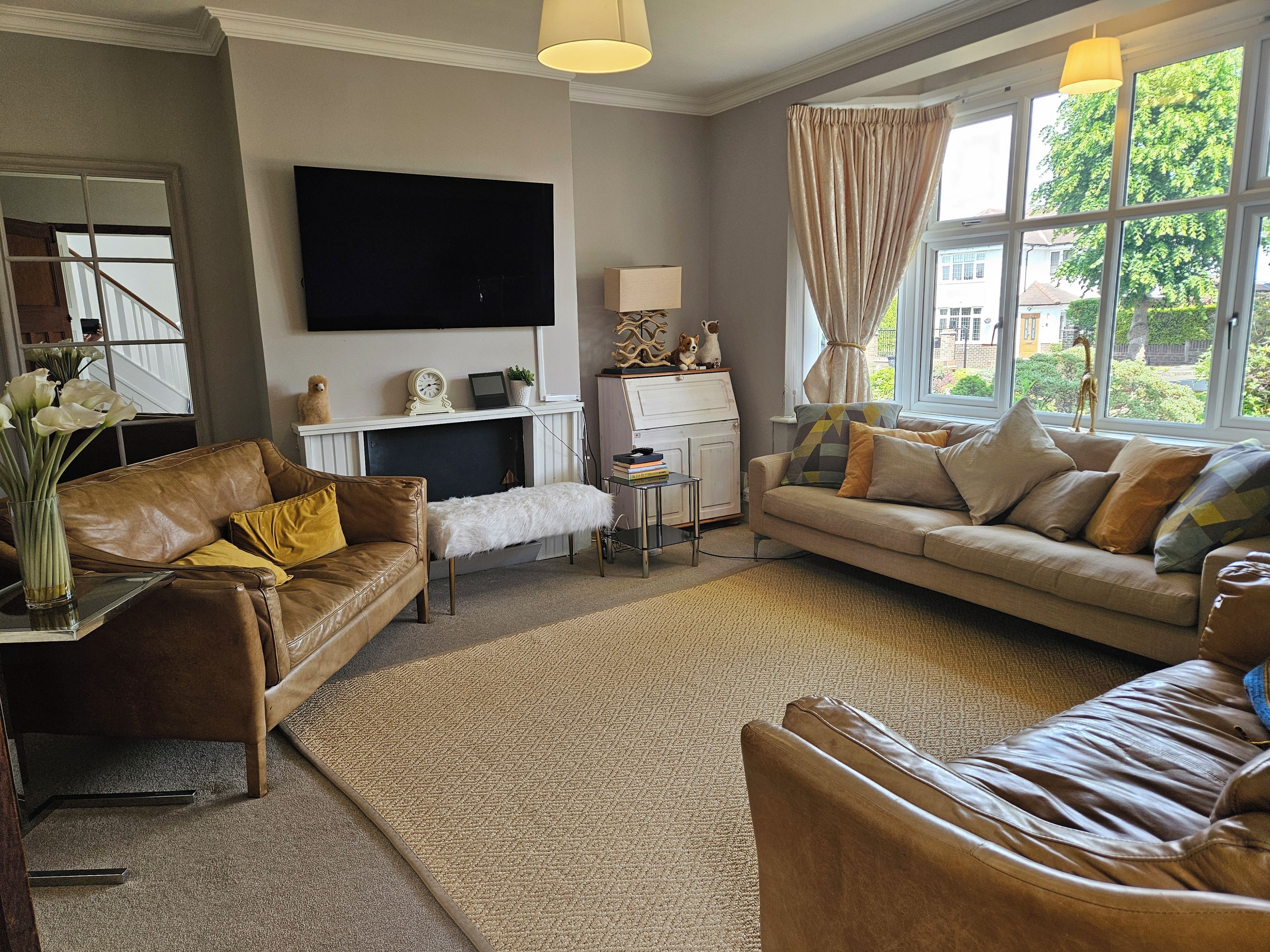 Ein Wohnzimmer mit Kamin, Sofas, einem Fernseher und Blick ins Freie.