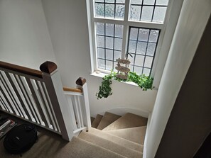 A staircase with a white railing, a window with frosted glass, and a hanging sign with the words "JOY LOVE PEACE". - Charming family home in the heart of Sanderstead. (Greater London)
