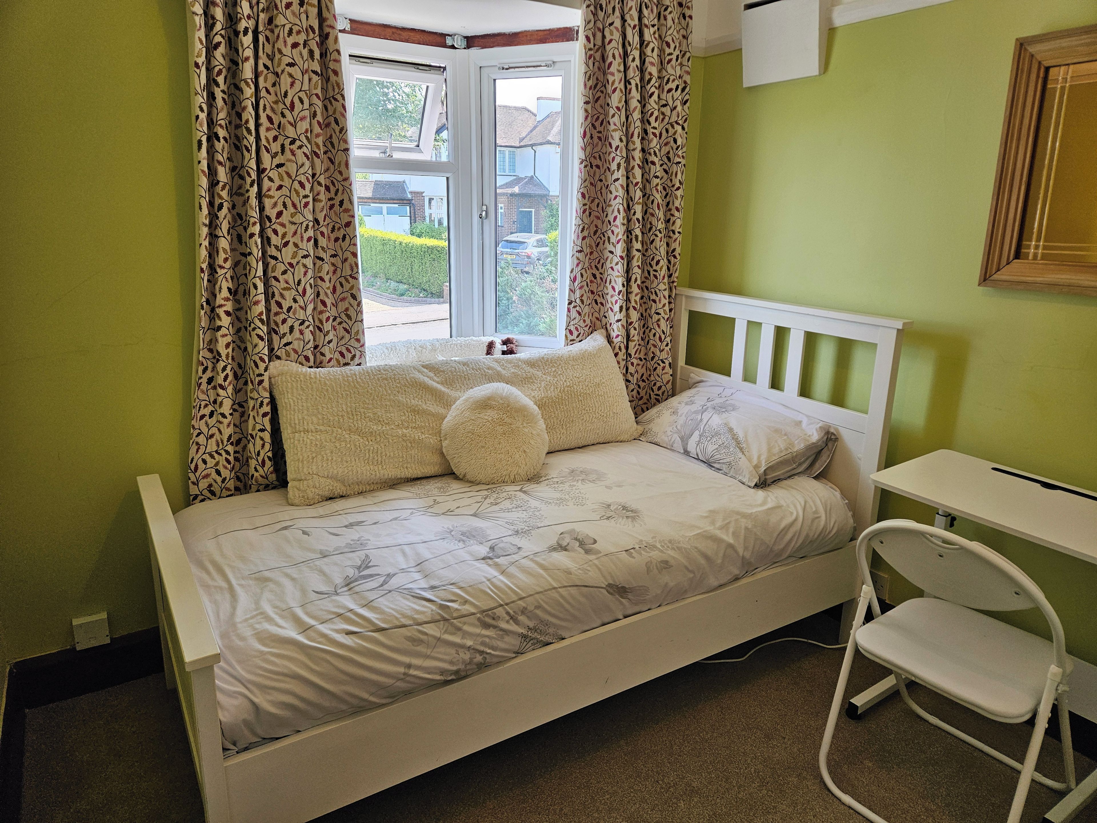 A single bed with a white frame, a small bedside table, and a chair.