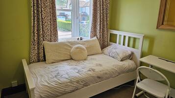 A single bed with a white frame, a small bedside table, and a chair.