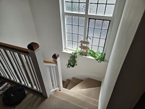 A staircase with a white railing, a window with frosted glass, and a hanging sign with the words "JOY LOVE PEACE". - Charming family home in the heart of Sanderstead. (Greater London)